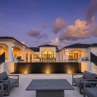 A Miami estate photographed at dusk, warm interior light on the terrace.